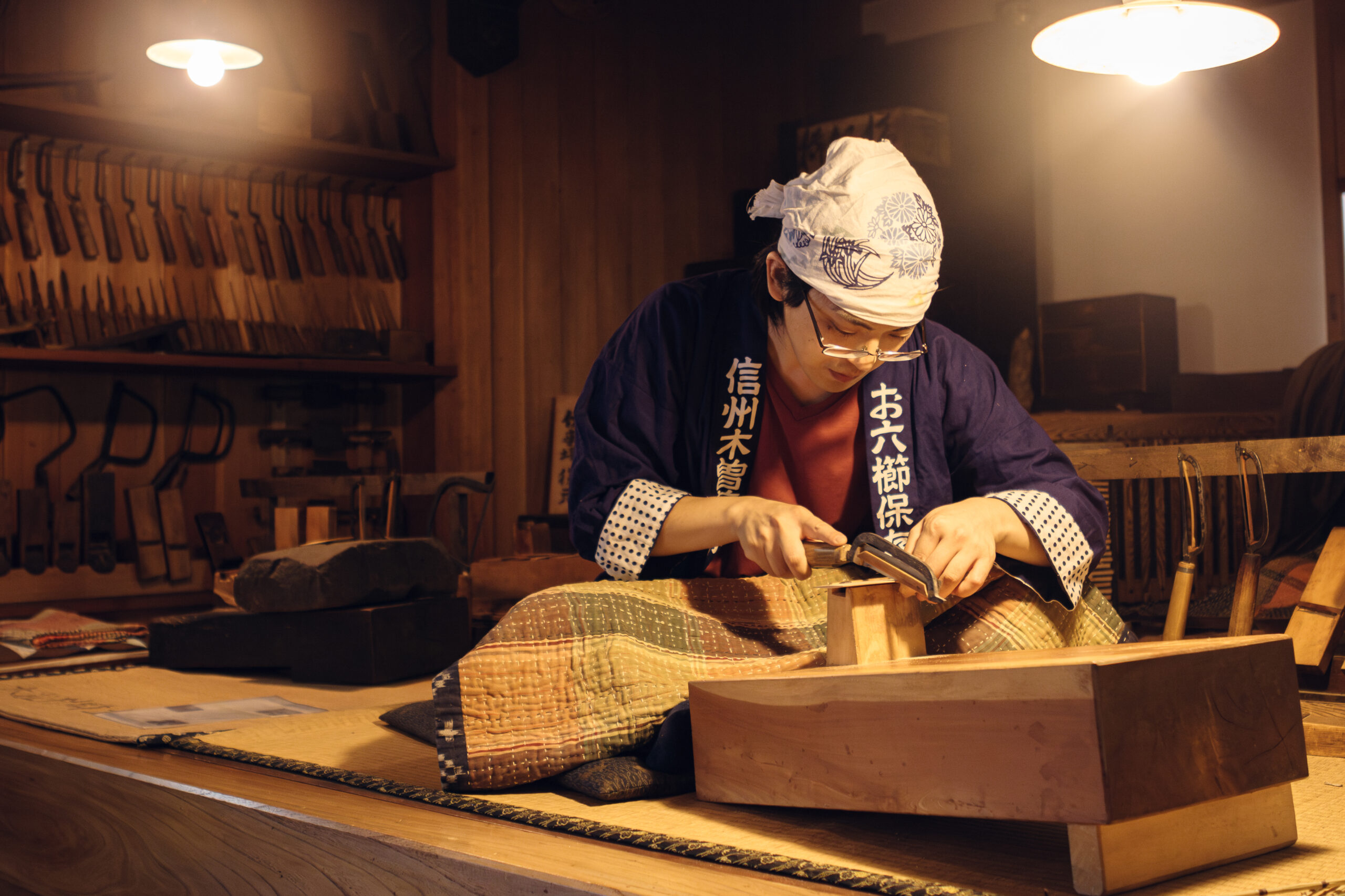 工房でお六櫛を挽く井上慧さん。手元と周囲の道具が見える活動風景